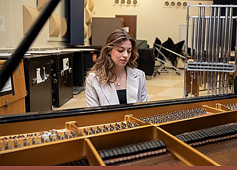 Arianna C. Gallo seated at the piano in a rehearsal space